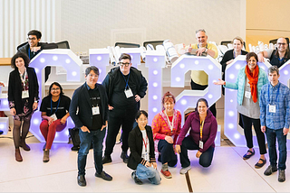 Members of the EC against the CHI2023 installation. Many of the members are wearing their EC “Doin’ the Work!” tshirts.