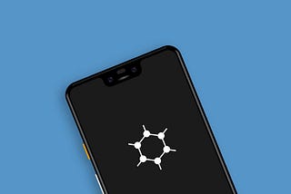 A blue background with the top half of a smartphone peeking from the bottom. The screen is blank with the exception of the GrapheneOS logo in the center. It is white and hexagonal, with nodes poking at every corner.