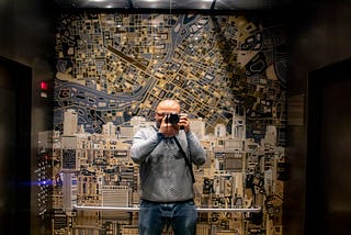 A self portrait in a mirror of an elevator of me in an elevator with a huge map of nashville behind me