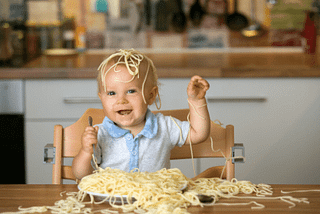 baby eating a plate of spaghetti