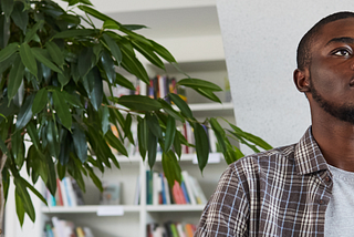 Low angle view at blind African-American man reading Braille book in school library.