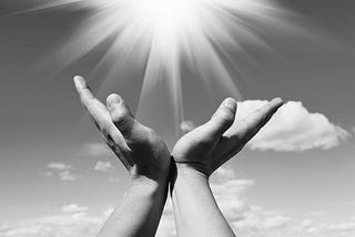 Hands held up to sky with light rays