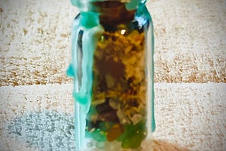 Small jar with crystals and herbs, sealed with green wax to make a money jar