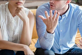 A man and a woman on a couch talking.