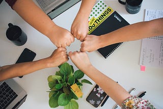 A circle of different people’s hands together in a circle to show camaraderie.