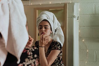 Woman putting on makeup in front of a mirror