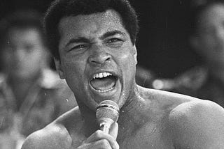 Muhammed Ali shouting into a microphone in his hand