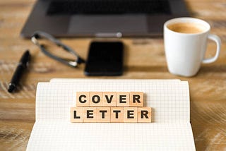 a cover letter on a wooden table next to a cup of coffee and a laptop
