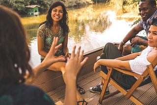 People sitting on a dock by a river, sharing stories