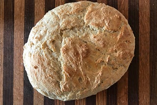 a loaf of strangely shaped fool-proof bread on a striped cutting board