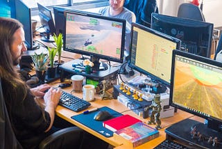 Shows Auroch Digital developer working on two computers.