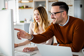 Professionals in business casual attire look at a desktop.