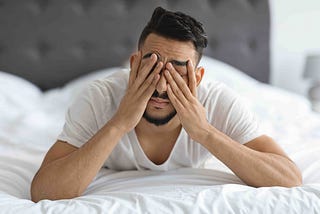 An anxious man holds his head in his hands.