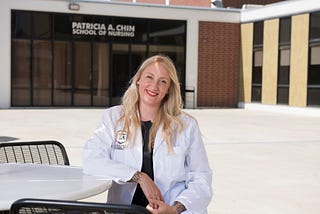 Cal State LA nursing major Alexandra Martin seated outdoors, in front of the Patricia A. Chin School of Nursing office.