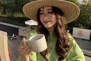 a girl holding a tea cup and worn hat