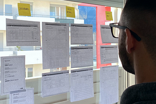 Person looking at some wireframes hanged on a large window.