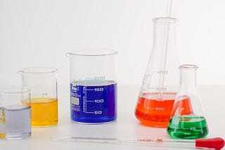 Five beakers and flasks filled with different colourful liquids.