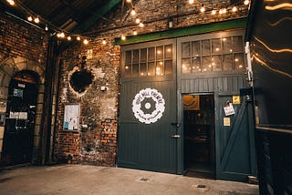 The outside of Hope Mill theatre — a mill building, decorated with strings of lights