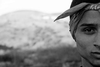 Black and white photo of half of a mans face wearing a bandana