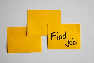 Stock photo of 3 yellow sticky notes. The third has the text “Find Job” written on it in sharpie.