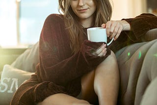 Gorgeous young woman on a sofa with a cup of coffee
