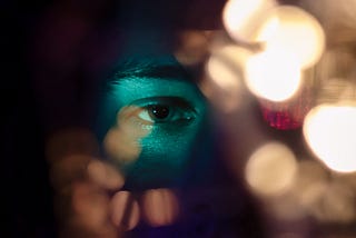 A person’s eye looking through multi colored lights