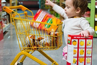 Small child using a child-sized shopping cart.