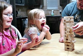 excited girl playing jenga with family