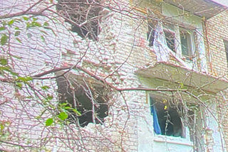 Side of a building with 2 gaping holes caused by a bomb