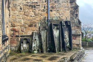 Empty stone coffins standing against the wall of Bakewell Church