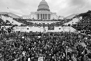 This photo shows the U.S. Capital as thousands of President Trump supporters, rioters, and insurrectionists gather to protest Biden’s election. At this point in the protest, they have breached the barriers, and are climbing over the steps. Some have made their way into the building, via breaking down doors and windows.