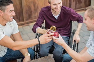 Man, on a wheelchair, enjoying his drink with friends.