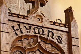 Color photo of the word Hymn carved in wood,  probably inside a church.