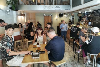 A busy tapas bar with wooden floor, tables and hard stools