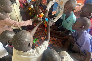 Learners are sitting one the floor in a circle, working with colorful building blocks