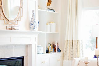 Bright and cheerful living room with white walls and cabinetry and blue and gold decor.