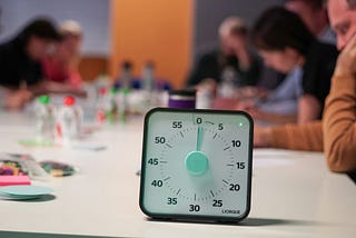 A bunch of poeople sitting aroudn a table with a timer in focus about to tick down.
