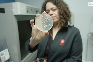 Sarah Richardson, CEO of MicroByre, holds up a petrie dish with bacterial cultures for the camera.