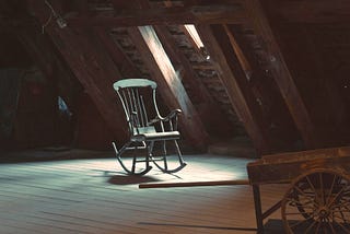 Rocking chair in a dusty attic beneath a window