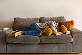 A woman cries and buries her head into a large stuffed teddy bear.