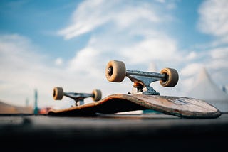 A close up of an abandoned skateboard, wheels up, looking battered.