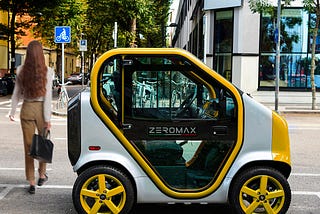 A view of a yellow and white ZEROMAX electric quadricycle parked by a crosswalk.