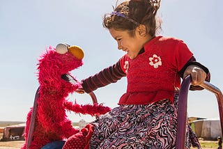 A young girl plays with Elmo