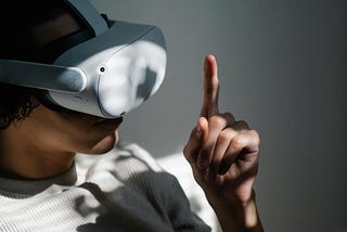 Person wearing virtual reality device and looking at their erect index finger.