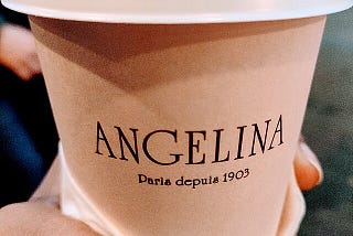 A brown paper cup saying “Angelina Paris depis 1903”