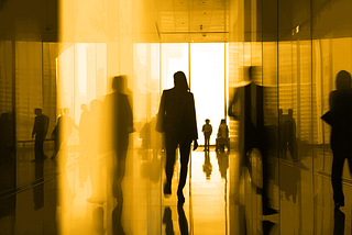 An artistic photograph of a silhouette of a person in a business suit walking in a company hallway.