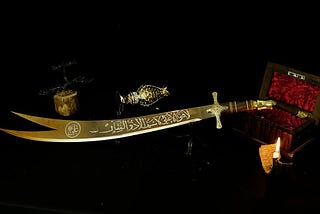 Zulfiqar, the most powerful sword in history, resting on a stand. The double-pointed blade is adorned with intricate Arabic inscriptions.