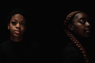 Two young African-American women posing in low light