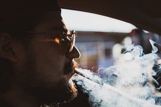 Profile of a man smoking and driving.