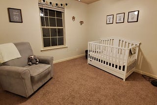 A photo of the room we have prepared for our foster child, including a crib, chair, and stuffed sloth.
